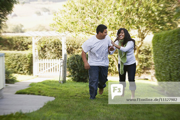 Hispanic brother and sister running on grass