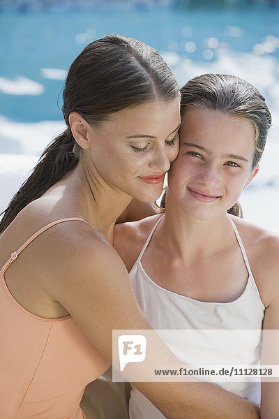 Gemischtrassige Frau und Tochter in Badeanzügen  die sich umarmen