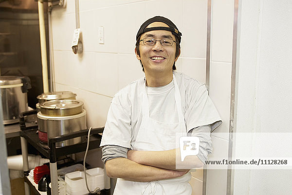 Japanischer Koch lächelt in Großküche