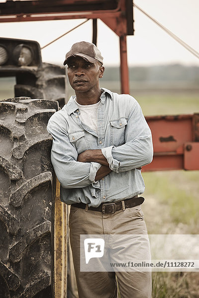 Afroamerikanischer Bauer steht neben Traktor