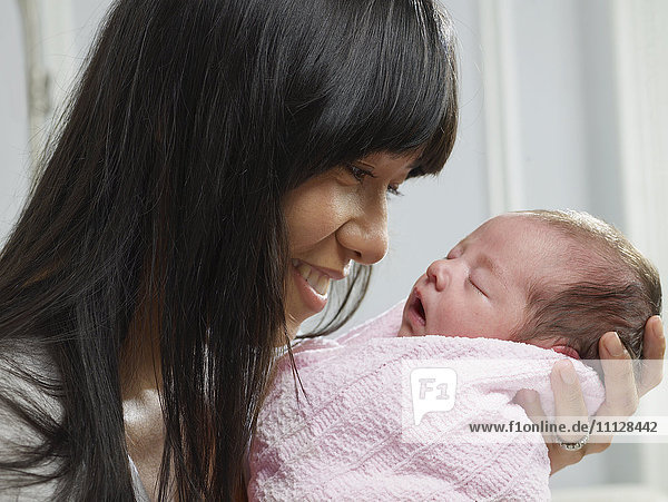 Mixed race mother cuddling newborn baby