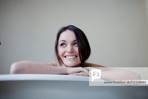 Caucasian woman leaning on side of bathtub
