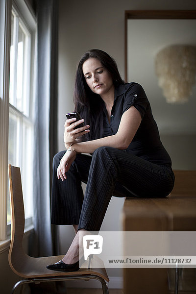 Caucasian businesswoman sitting in table using cell phone