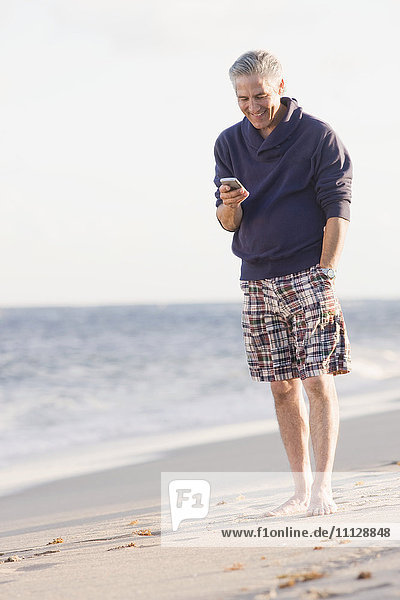 Mann benutzt Mobiltelefon am Strand