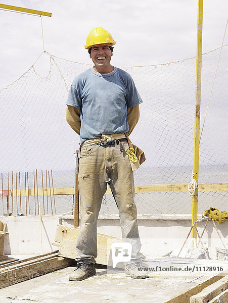 Hispanischer Arbeiter lächelt auf der Baustelle
