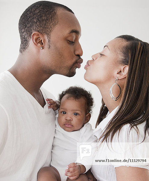 African couple holding baby and kissing