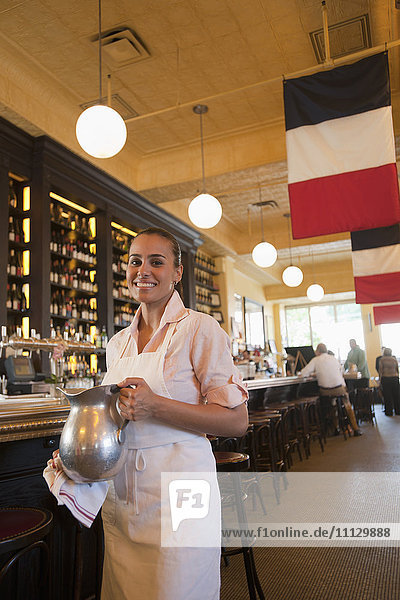 Hispanic waitress holding pitcher in restaurant