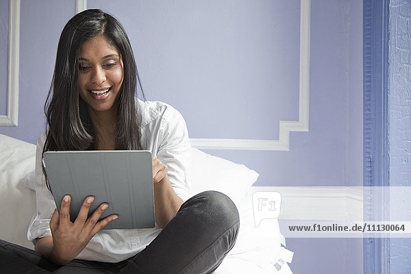 Sri Lankische Frau auf dem Bett mit digitalem Tablet