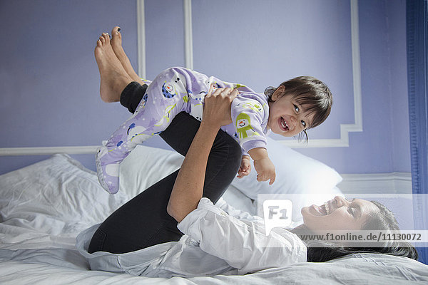Sri Lankan mother playing with baby girl on bed