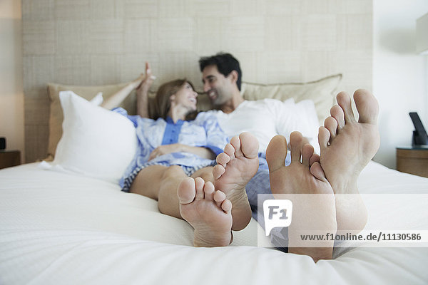 Hispanic couple laying on bed with bare feet