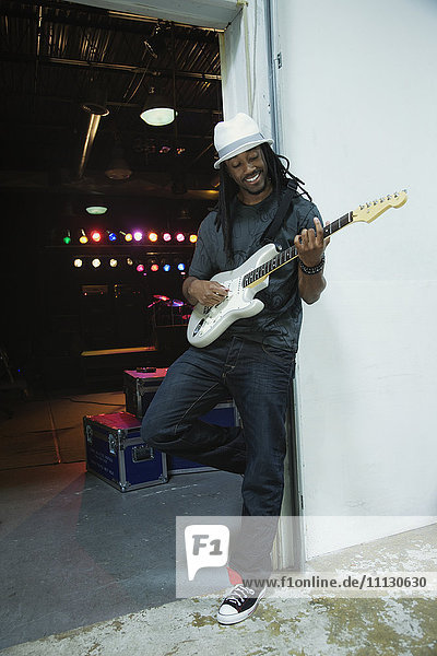 Afrikanischer Mann spielt E-Gitarre hinter der Bühne
