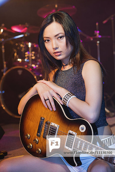 Asiatische Frau mit E-Gitarre