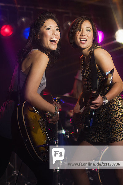 Asian women playing electric guitar onstage