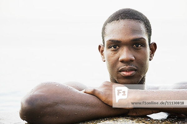Afrikanischer Mann lehnt sich an den Rand eines Schwimmbeckens