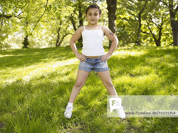 Mixed race girl with hands on hips in grass