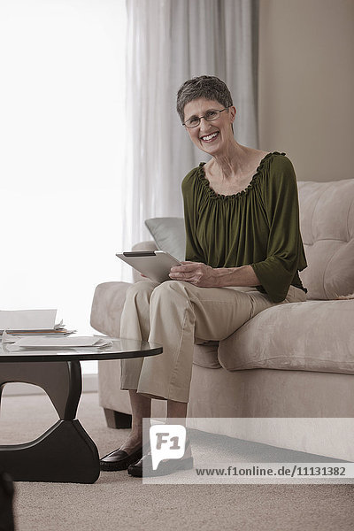 Kaukasische Frau mit digitalem Tablet auf dem Sofa