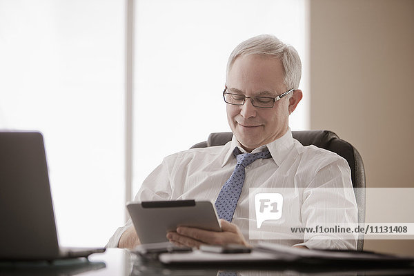 Caucasian businessman using digital tablet at desk