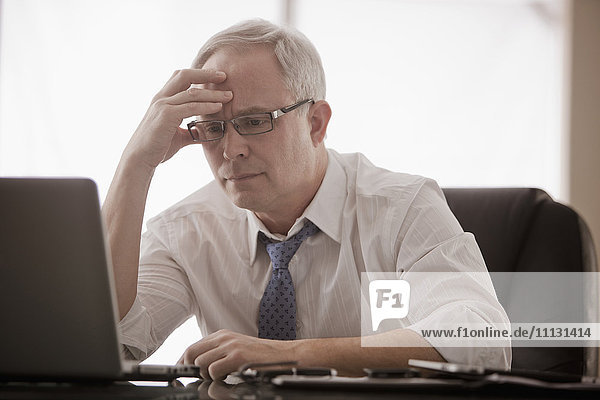 Frustrated Caucasian businessman using laptop at desk
