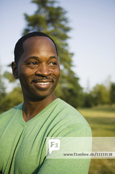 Lächelnder afroamerikanischer Mann im Park stehend