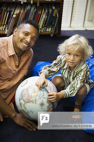 Vater und Sohn mit Globus in der Bibliothek