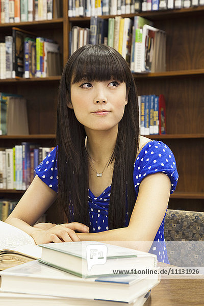 Asiatische Frau macht Hausaufgaben in der Bibliothek