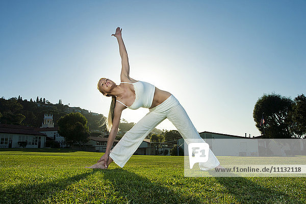 Caucasian woman practicing yoga in field