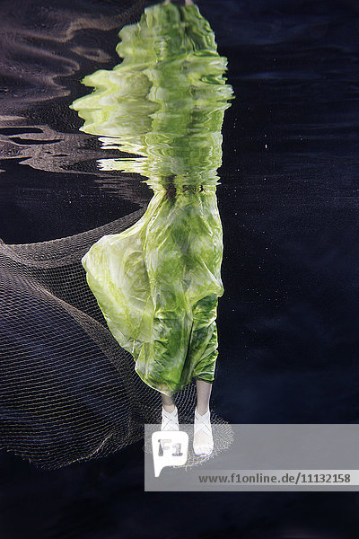 Gemischtrassige Frau im Kleid schwimmt unter Wasser
