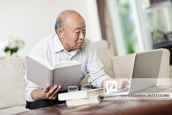 Chinesischer Mann mit Buch und Laptop