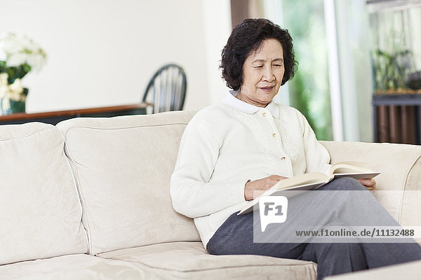 Chinese woman on sofa reading book