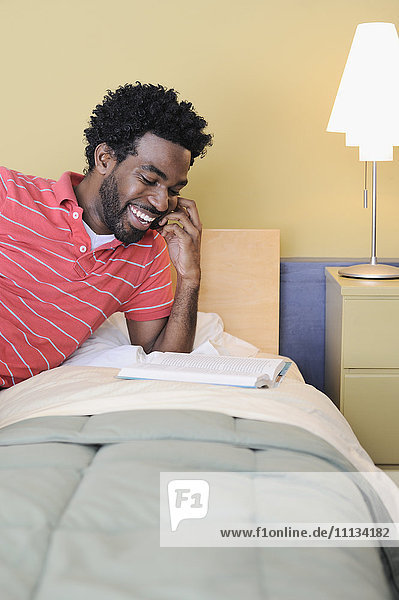 Black man in bedroom talking on cell phone