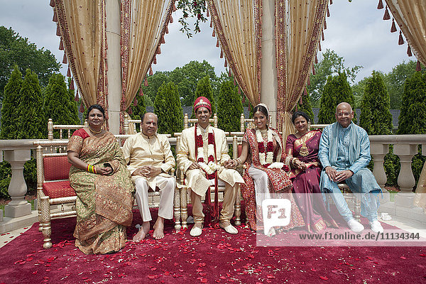 Indische Braut und Bräutigam mit Familie in traditioneller Kleidung