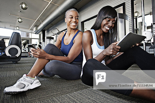 Women using digital tablet in health club