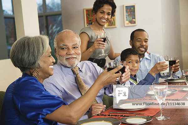 African American family toasting with wine at dining table