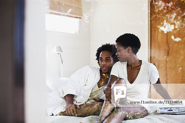African American woman sitting on bed with boyfriend