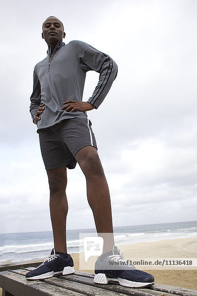 Schwarzer Mann steht auf einer Bank am Strand