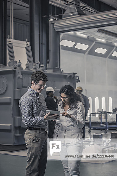 Arbeiter benutzen gemeinsam ein digitales Tablet in einer Fabrik
