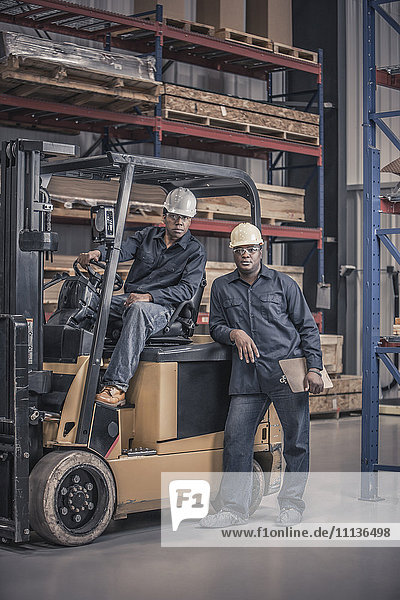 African American workers with forklift in factory
