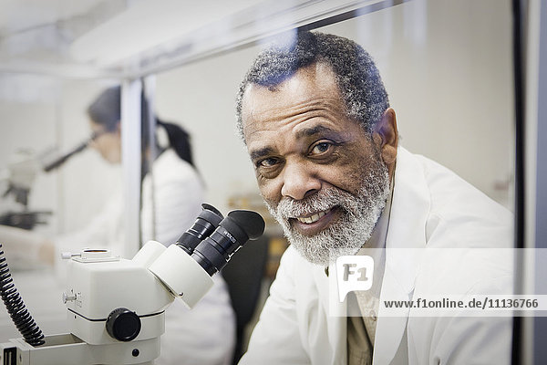 Afroamerikanischer Wissenschaftler mit Mikroskop im Labor