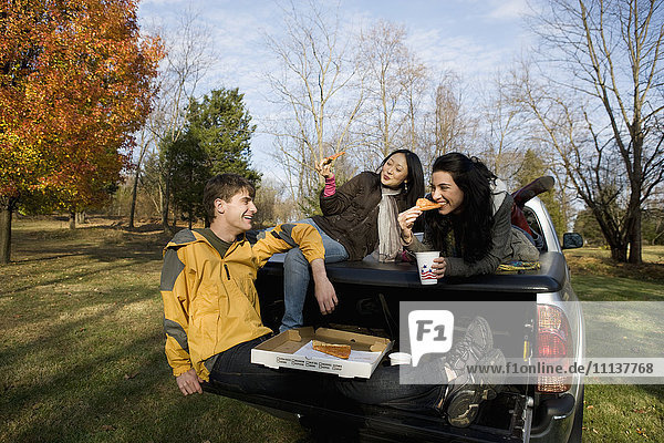 Friends eating pizza in back of truck