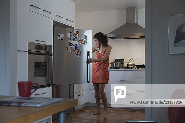 Woman in nightgown looking for food in refrigerator