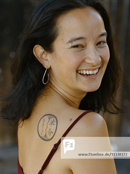 Smiling mixed race woman with tattoo