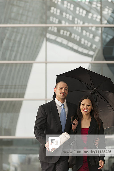 Geschäftsleute stehen mit Regenschirm zusammen