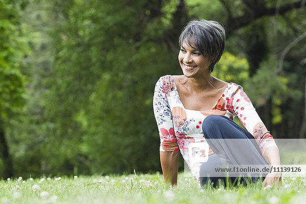 Smiling mixed race woman sitting in field