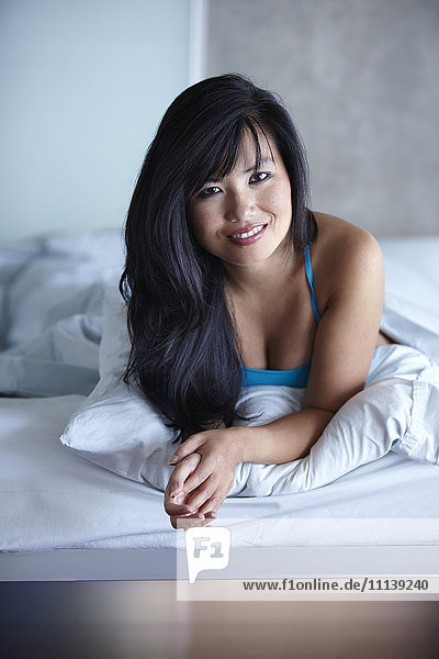 Lächelnde Frau im Bett liegend