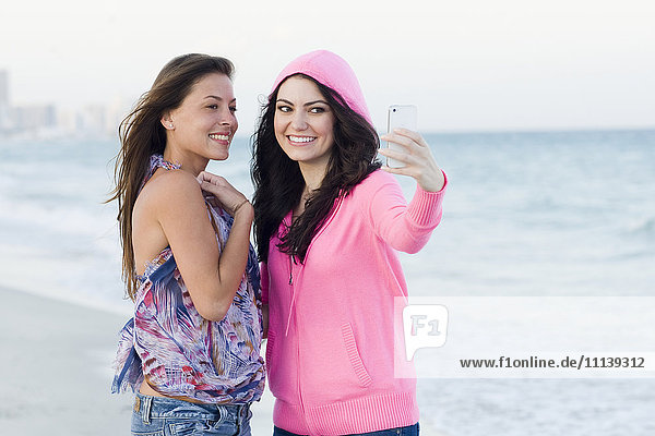 Frauen fotografieren gemeinsam am Strand