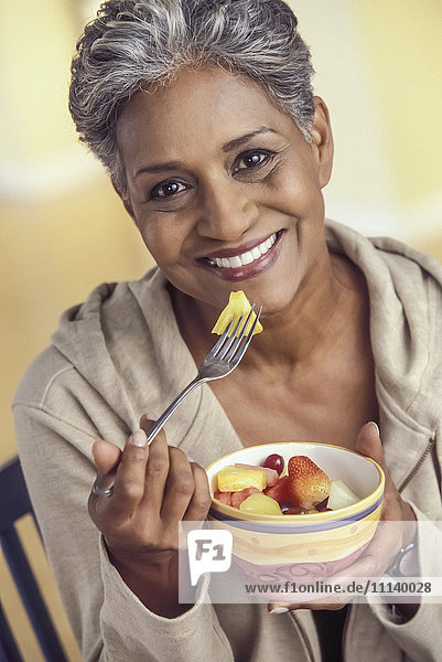 Older woman eating bowl of fruit