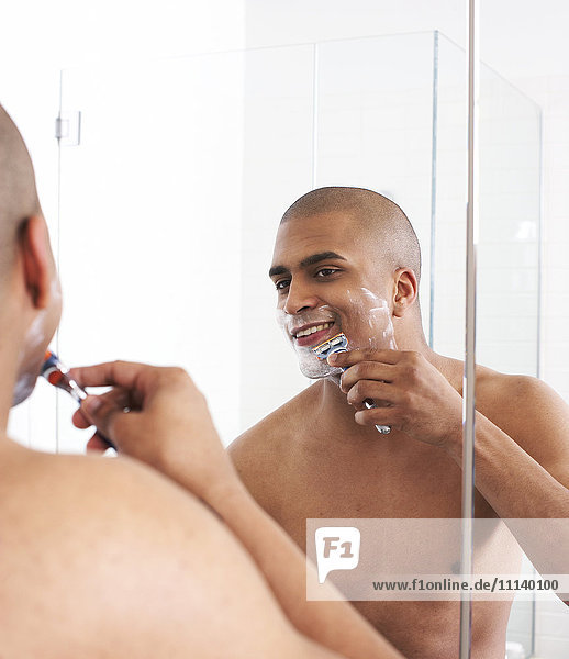 Man shaving in bathroom mirror