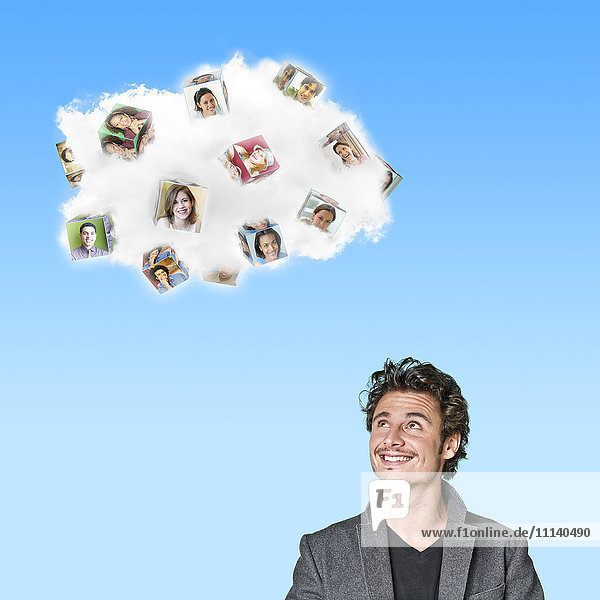 Caucasian man looking at cloud containing cubes with pictures of people
