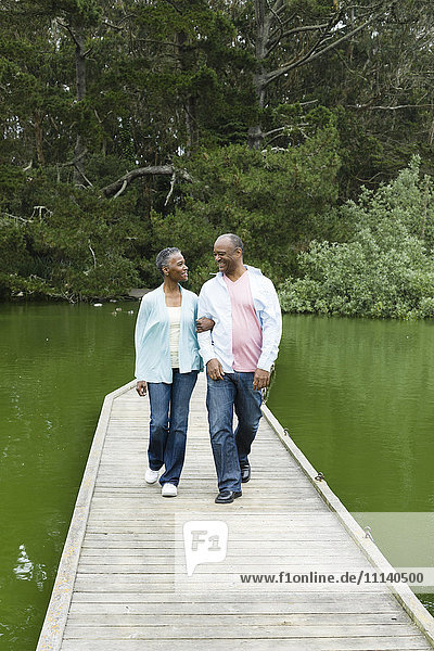 Lächelndes afroamerikanisches Paar auf einem Steg am See