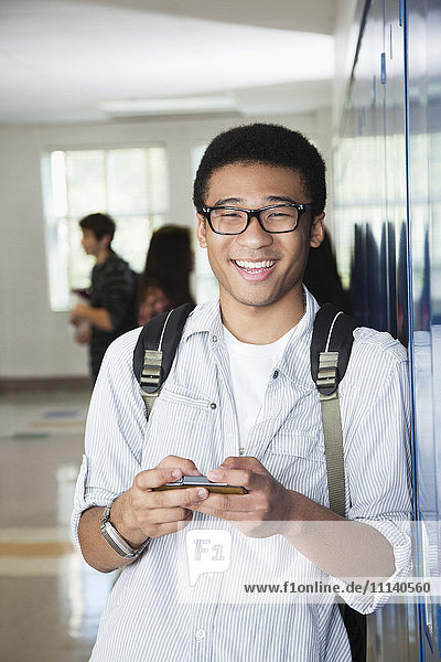 Mixed race high school student text messaging on cell phone